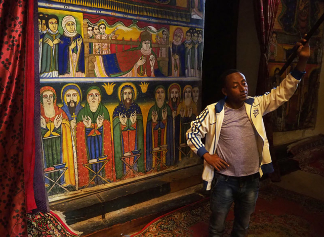 A guide lifts a curtain to reveal frescoes inside the 17th century Cathedral of St Mary of Zion in Axum, northern Ethiopia.