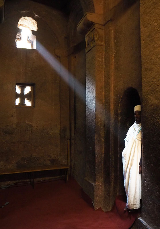 A ray of sunlight illuminates a priest in a rock-hewn church in Lalibela.