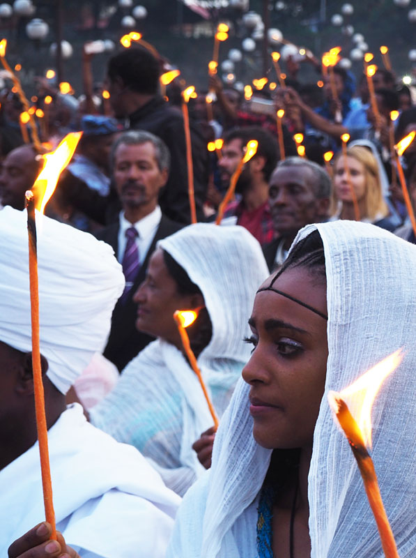 Festival-goers light candles as the demera, a ritual bonfire, starts to burn.