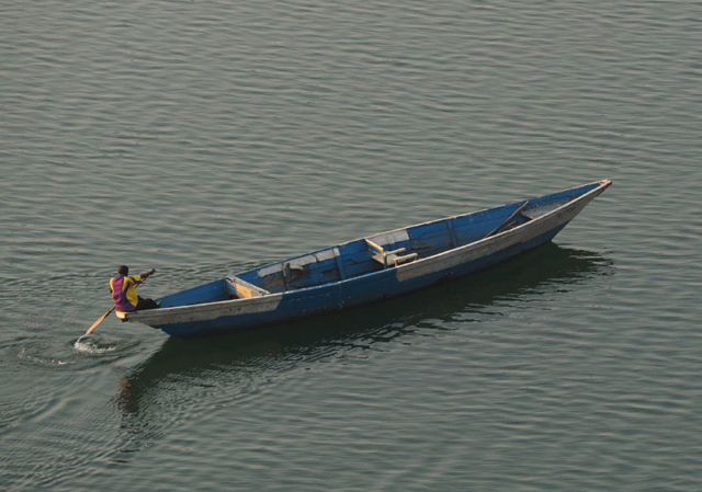 A man paddles a boat on Lake Kivu at dawn.