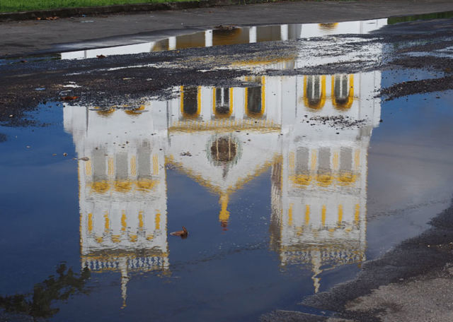 A church is reflected in a puddle in Leone village.