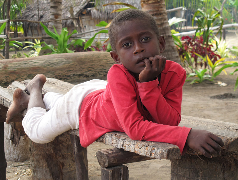 A child chills out on a bench in the Maskelyne Islands
