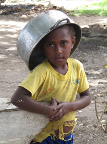 A boy turns a cooking pot into a hat in the Maskelyne Islands