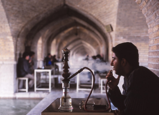 A man smokes a qalyan in a tea house under the arches of the 17th century Si-o-Seh Bridge in Esfahan