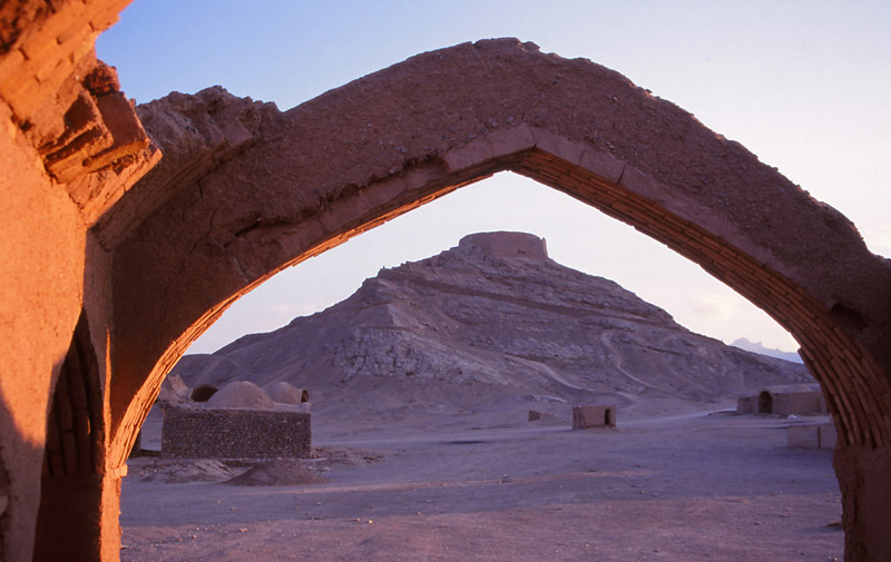 A Zoroastrian Tower of Silence is framed by a ruined arch in Yazd