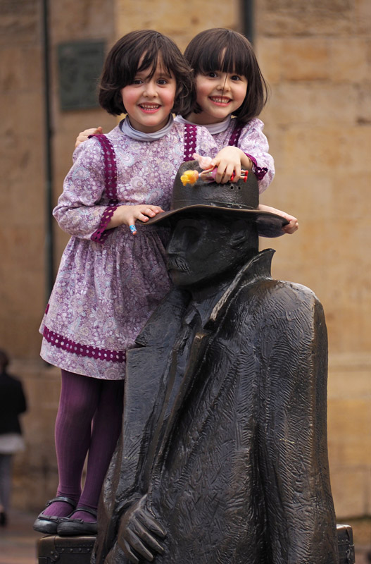 Twins play on a statue in Oviedo, northern Spain