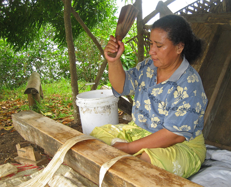 A woman beats paper mulberry bark into tapa cloth, Tongatapu Island