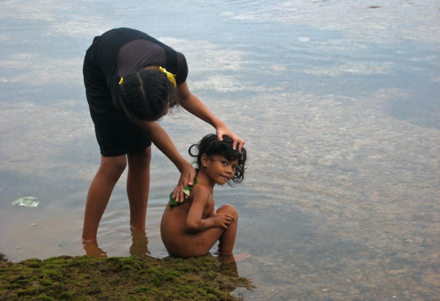 A girl washes her sister in a rock pool at Toula village, Vava’u