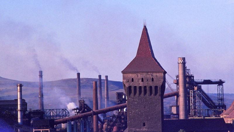 Furnace chimneys loom over medieval castle towers at Hunedoara