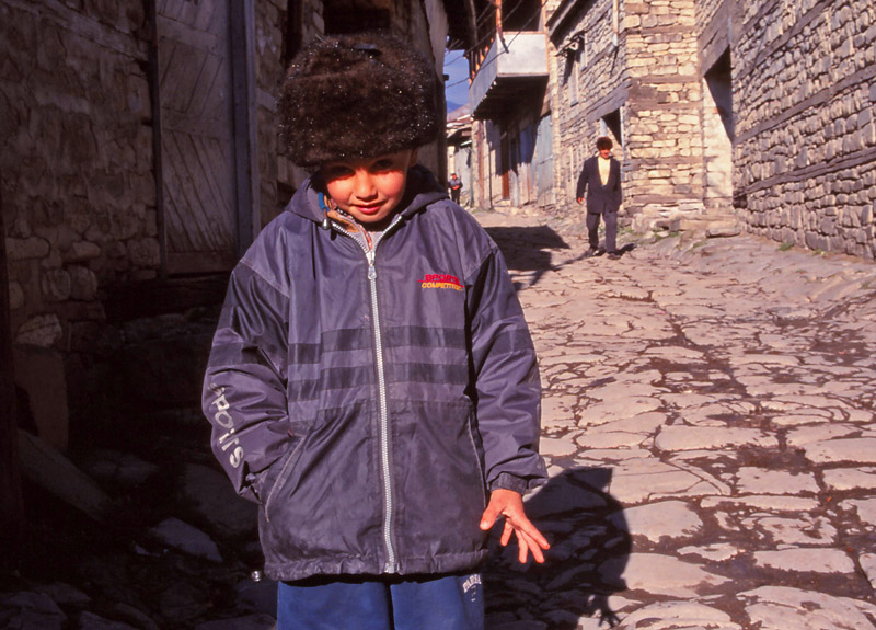 A boy keeps warm on the main street of Lahıc