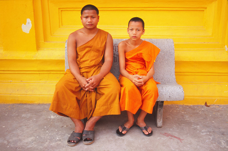 Monks share a bench at a monastery in Vientiane