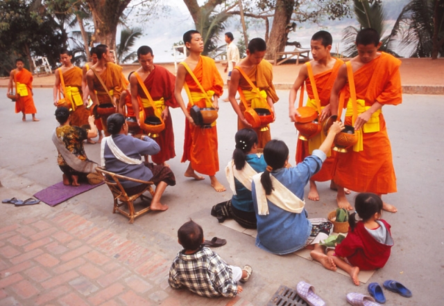 Devout Buddhists offer monks gifts of sticky rice at dawn in Luang Prabang