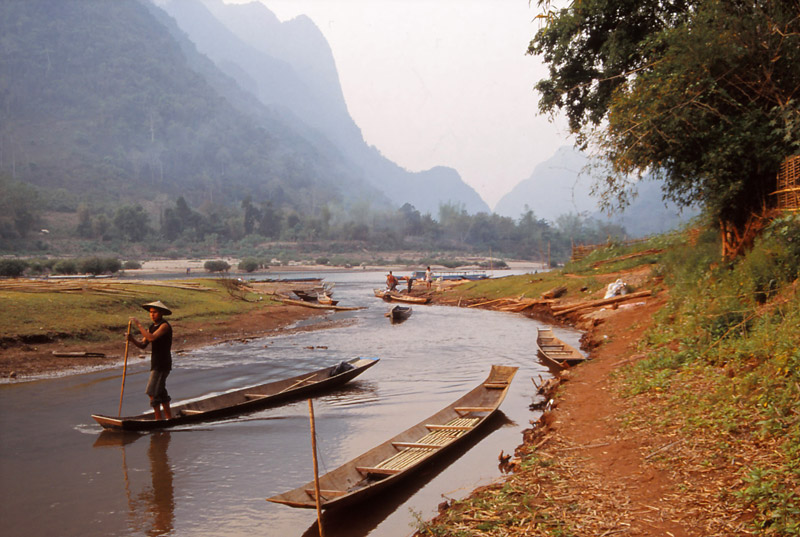 A man punts a boat on the Nam Ou River
