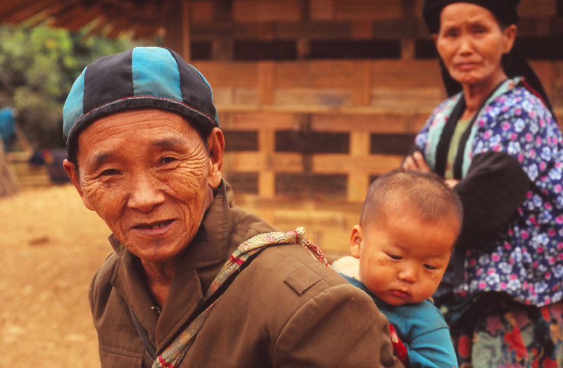 A man carries his grandchild in a Hmong highland village