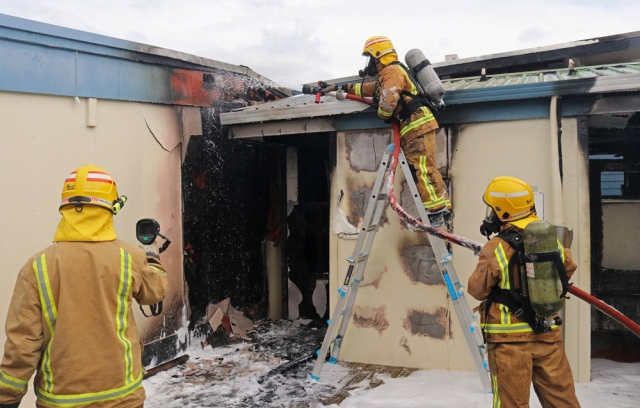 October: Volunteer firefighters hose down a toilet block and check for hotspots during a fire at Kerikeri High School. Photo: Peter de Graaf