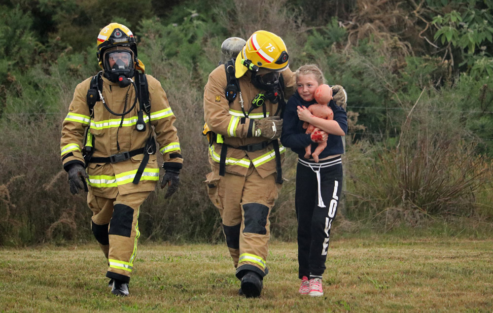November: Firefighters lead 11-year-old HannahKate to safety during a crash simulation at Bay of Islands Airport in Kerikeri. Photo: Peter de Graaf