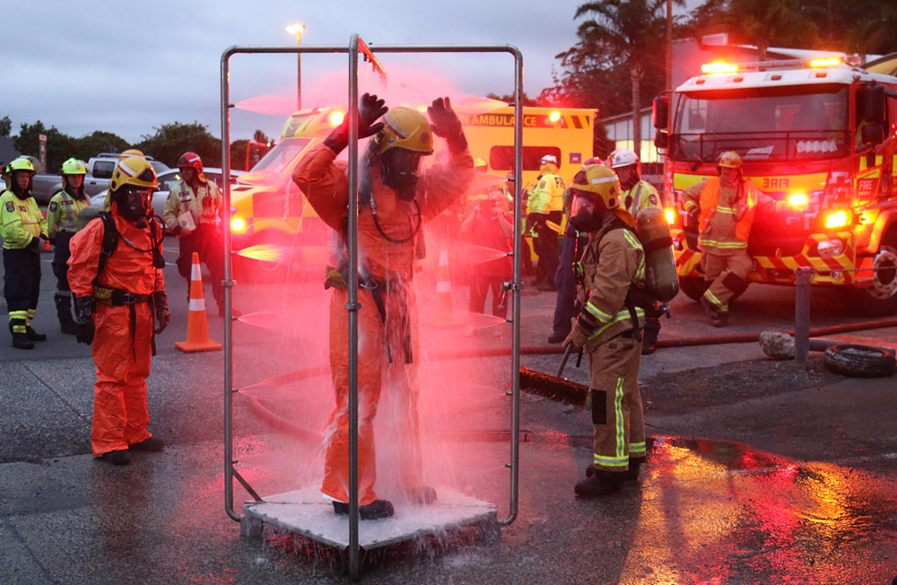 March: Firefighters wash off in a decontamination shower during a chemical spill exercise in Kerikeri. Photo: Peter de Graaf