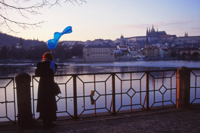 A woman holds a rabbit balloon by the Vltava River, Prague