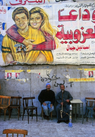 Cairo cafe patrons enjoy a sheesha or water pipe below a movie poster