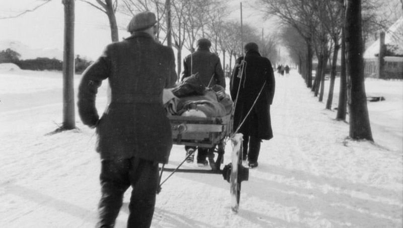 Men pull a cart of food through the snow in early 1945